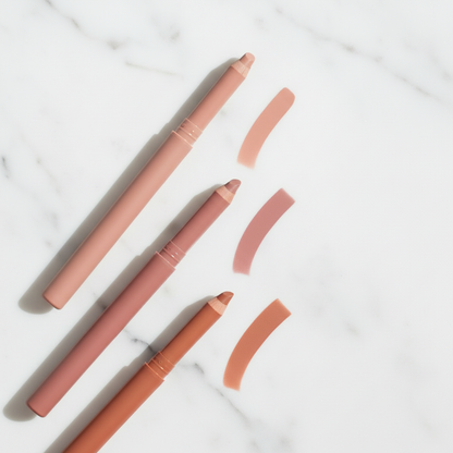Three lip liner pencils in nude beige, dusty rose and terracotta brown on white marble